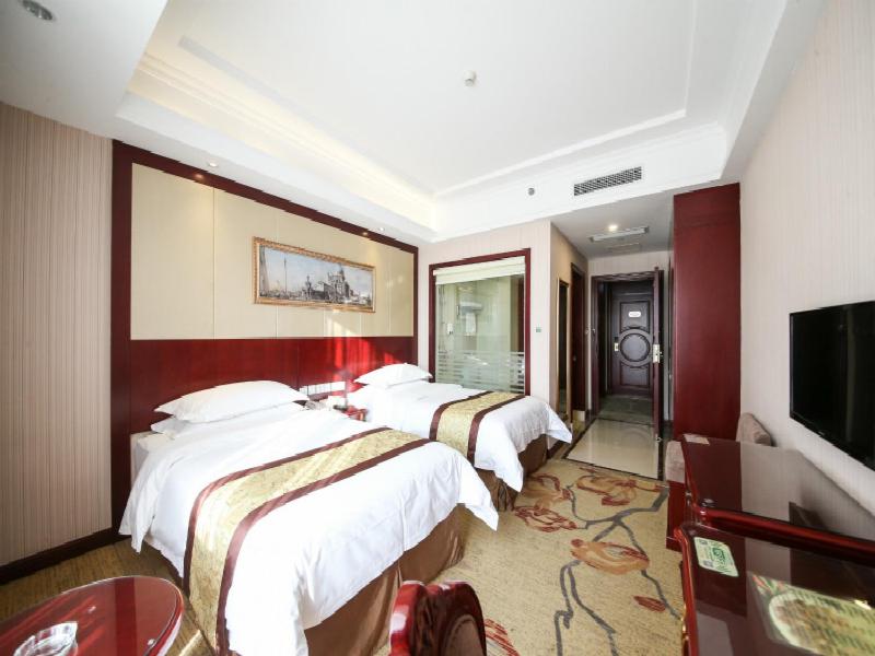 een hotelkamer met 4 bedden en een flatscreen-tv bij Vienna Hotel Shanghai Hongqiao Convention & Exhibition Center in Shanghai