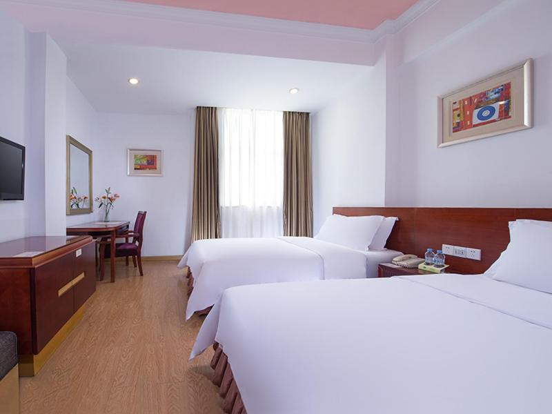 a hotel room with two beds and a desk at Vienna 3 Best Hotel Foshan Nanhai Film Studio City in Nanhai
