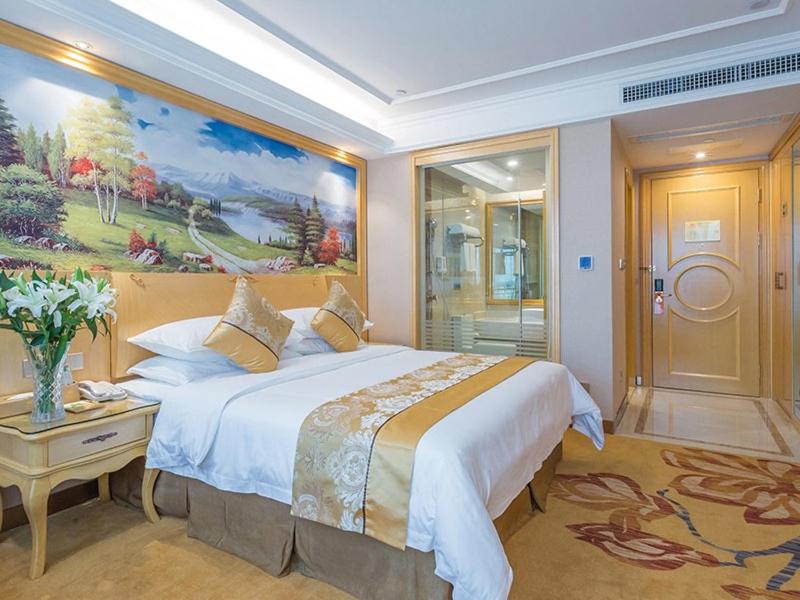 - une chambre avec un grand lit et une peinture murale dans l'établissement Vienna Hotel Guangxi Nanjing Nanhu Park, à Nanning