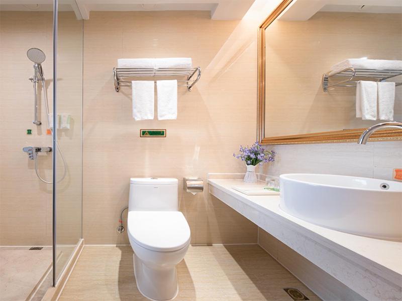 a bathroom with a toilet and a sink and a mirror at Vienna Hotel (Huizhou Daya Bay Xinyi Store) in Huizhou