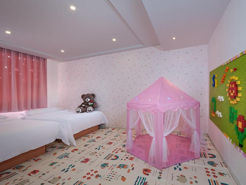a pink bedroom with two beds and a teddy bear at Vienna 3 Best Hotel Beihai Sichuan Road in Beihai