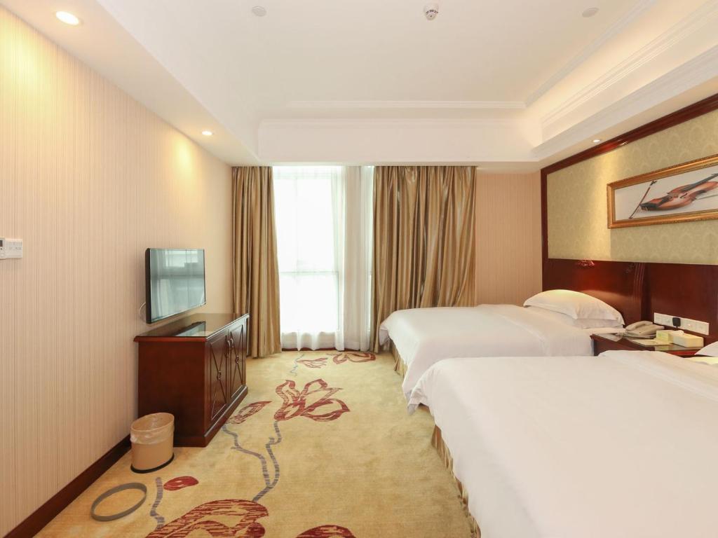 um quarto de hotel com duas camas e uma televisão em Vienna Hotel Guangzhou Dongpu Bus Station em Guangzhou