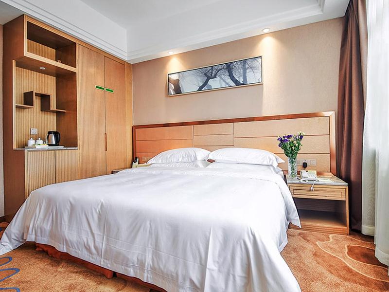 um quarto com uma grande cama branca num quarto em Vienna International Hotel Huhan Jiedaokou em Wuhan