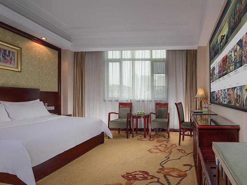 une chambre d'hôtel avec un lit, une table et des chaises dans l'établissement Vienna Hotel Zhongkai Road Branch, à Huizhou