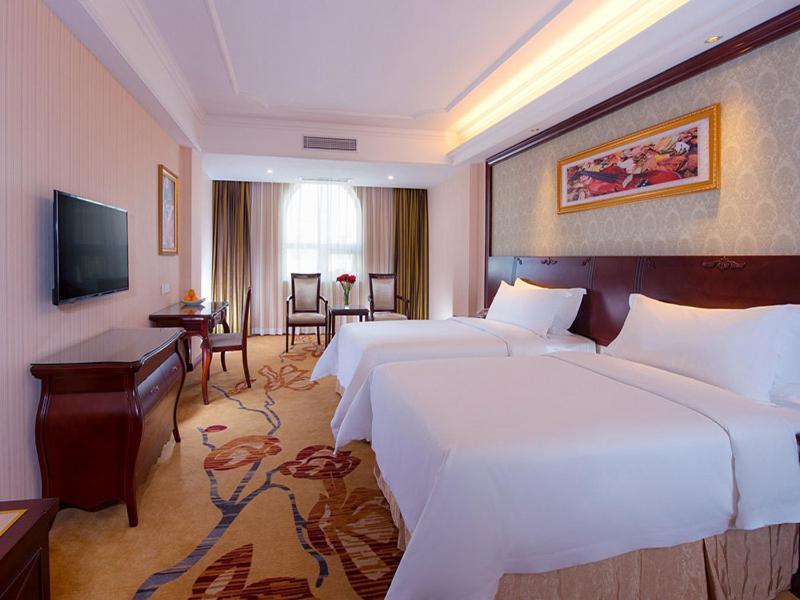 a hotel room with two beds and a desk at Vienna Hotel Guangzhou Shiling in Huadu