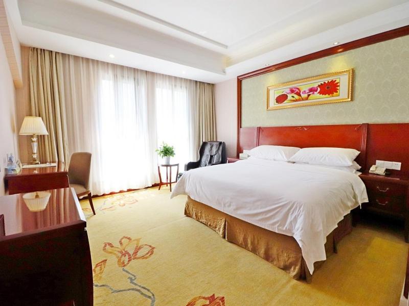 Habitación de hotel con cama grande y ventana grande. en Vienna Hotel Shanghai Hongqiao National Convention Centre en Shanghái