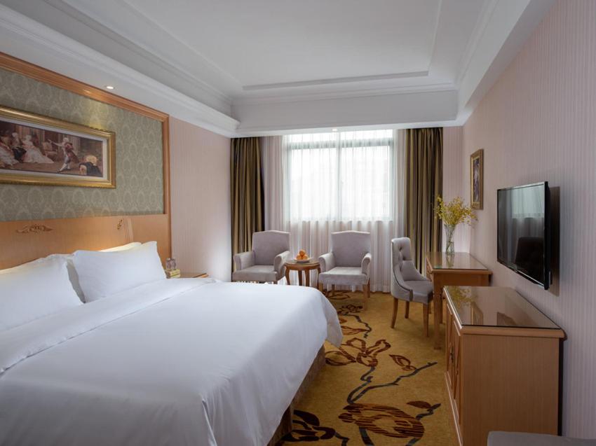 a hotel room with a large bed and a television at Vienna Hotel Shenzhen Buji Ganli Road in Longgang