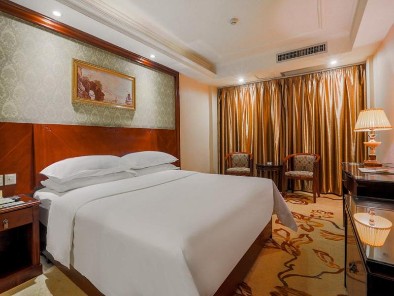 a bedroom with a large white bed and a desk at Vienna Hotel Guilin Railway Staion in Guilin