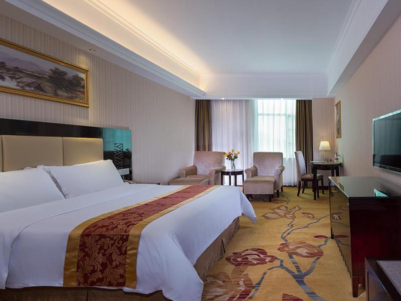 a hotel room with a large bed and a living room at Vienna Hotel Baoan Liutang in Xin'an