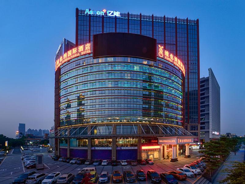a large building with cars parked in a parking lot at Vienna International Hotel Foshan Qiandeng Lake in Foshan