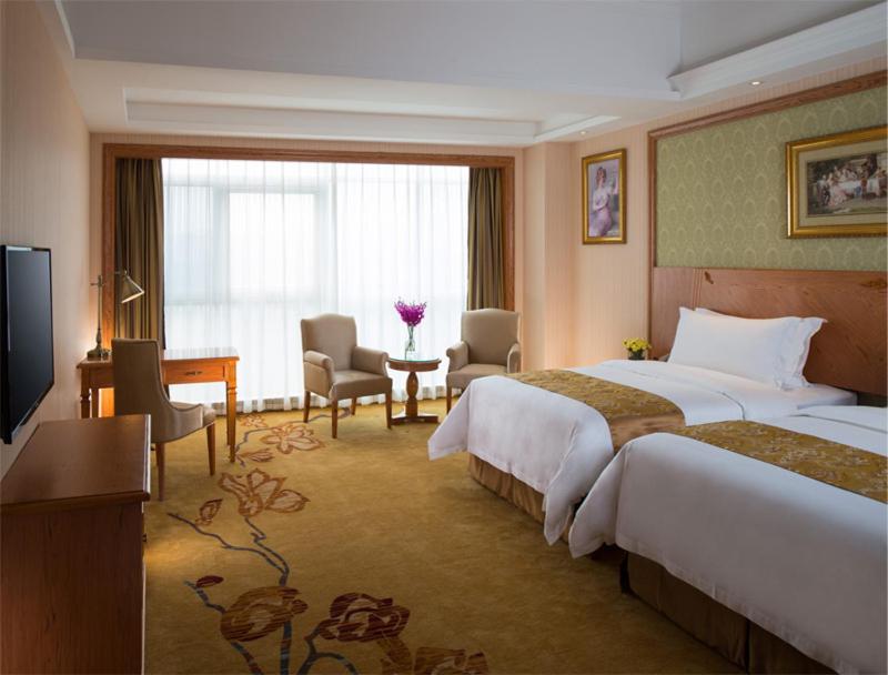 a hotel room with two beds and a desk at Vienna International Hotel Shenzhen Longgang Lilang in Longgang