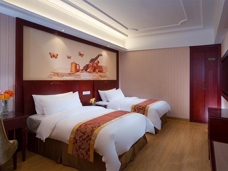 a hotel room with two beds and a painting on the wall at Vienna Hotel Shenzhen Exhibitian Center 2nd in Shenzhen