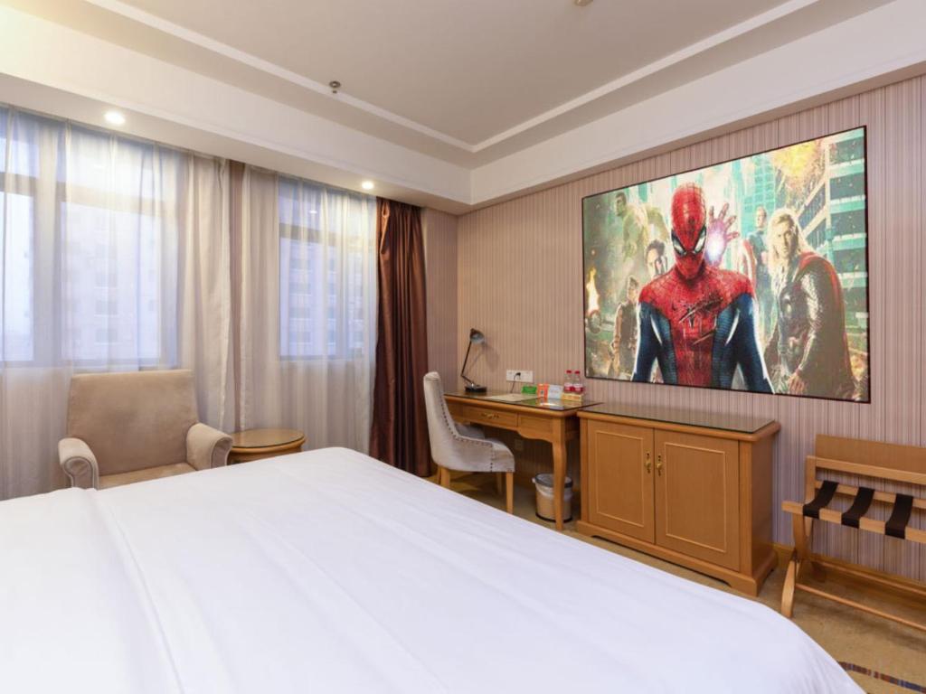 深セン市にあるVienna Hotel Shenzhen East Railway Stationのベッドと大画面スクリーン付きのホテルルームです。