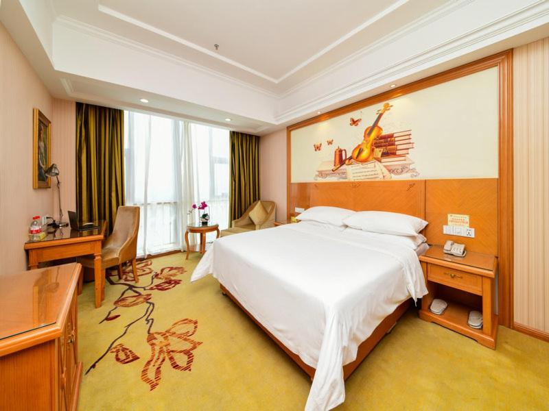 um quarto de hotel com uma cama grande e uma secretária em Vienna Hotel Kunshan North Qingyang Road em Kunshan