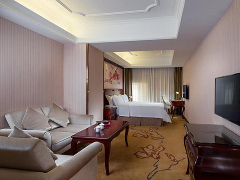 Habitación de hotel con cama y sala de estar. en Vienna Hotel Shenzhen Shuiku New Village en Shenzhen