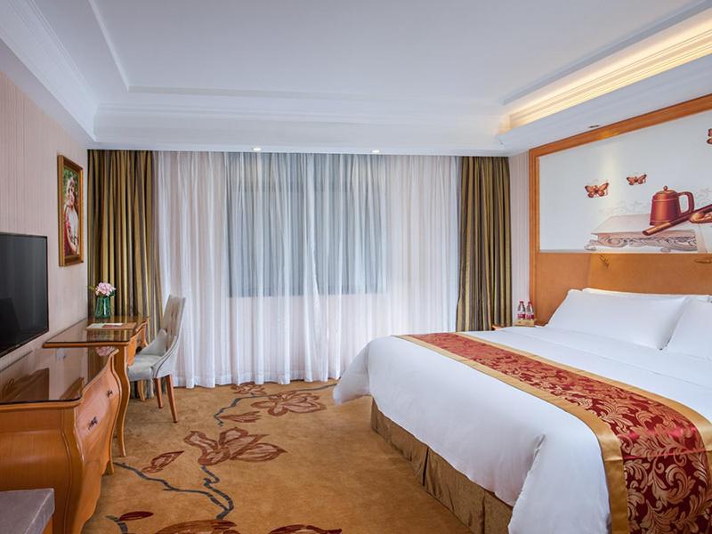 a hotel room with a large bed and a desk at Vienna Hotel Shenzhen Gongming Huafa North Road in Xitian