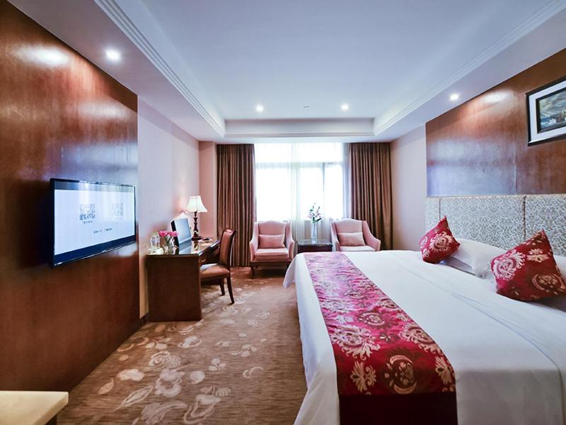 um quarto de hotel com uma cama e uma televisão de ecrã plano em Vienna Hotel Nanning Jiangnan Wanda em Nanning