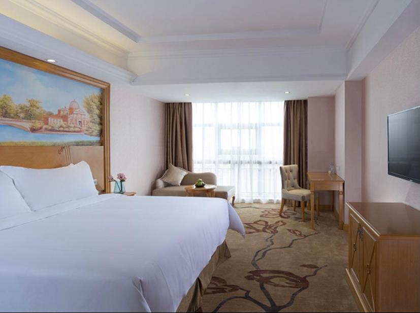 a hotel room with a large bed and a television at Vienna International Hotel Guangdong Foshan Nanhai Heshun in Nanhai