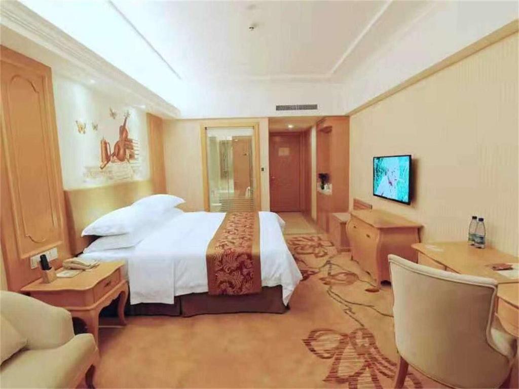 Großes Hotelzimmer mit einem Bett und einem Schreibtisch. in der Unterkunft Vienna Hotel Hunan Yongzhou Lengshuitan District Government Square in Guzhuting