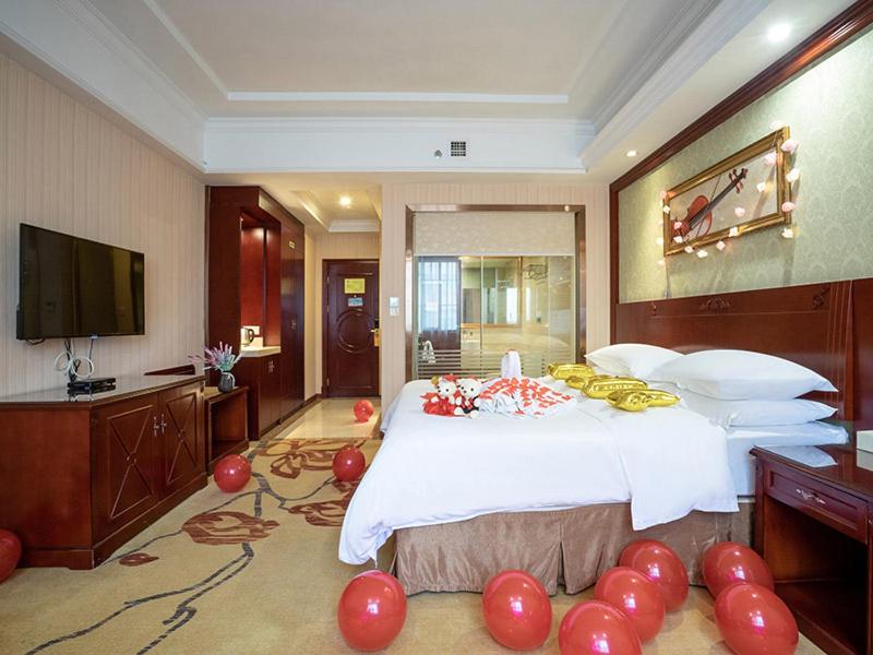 Vienna Hotel Nanning Xianhu في نانينغ: غرفة نوم بسرير كبير ويوجد بالونات حمراء على الارض