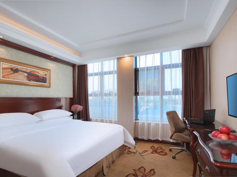 a hotel room with a bed and a desk and window at Vienna Hotel Nanjing Baijiahu Ximenzi in Nanjing