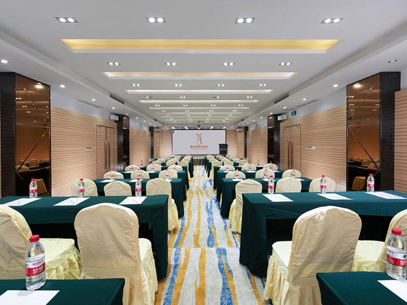 a conference room with tables and chairs and a screen at Vienna Hotel Shiyan Guangming Road in Bao'an