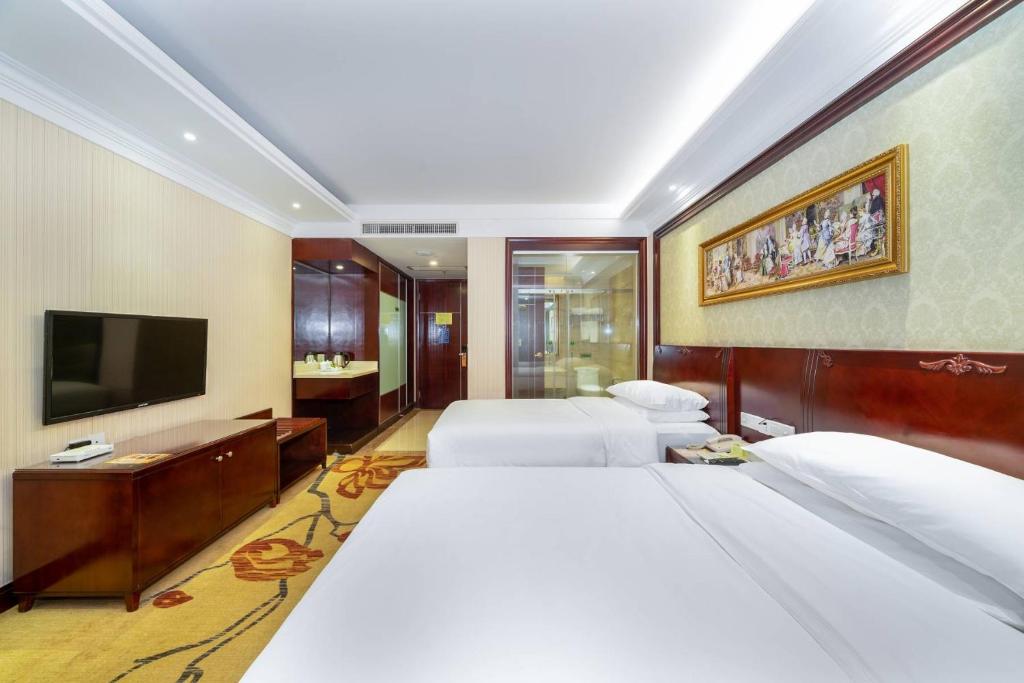 a hotel room with three beds and a flat screen tv at Vienna Hotel Dongguan Houjie Exhibition Center in Dongguan