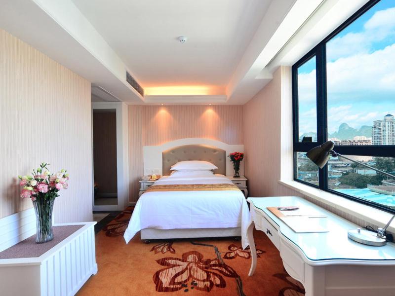 a bedroom with a bed and a desk and a window at Vienna Hotel Guangxi Guilin in Guilin