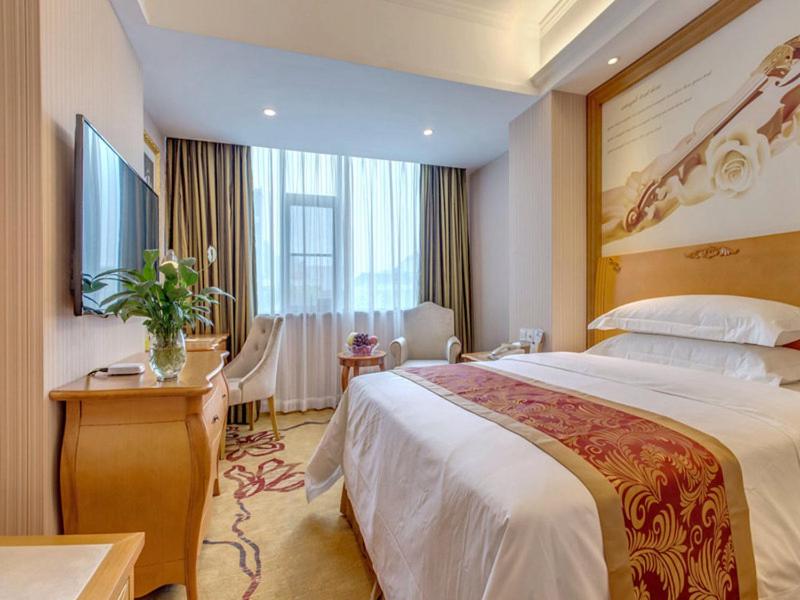 ein Hotelzimmer mit großem Bett und Schreibtisch in der Unterkunft Vienna Hotel Guilin AIrport Road Rongshan in Guilin
