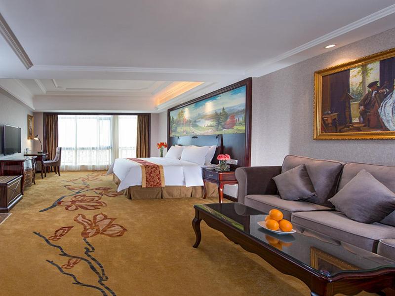 a hotel room with a bed and a couch at Vienna International Hotel Huizhou Huidong Honghaiwan in Huidong