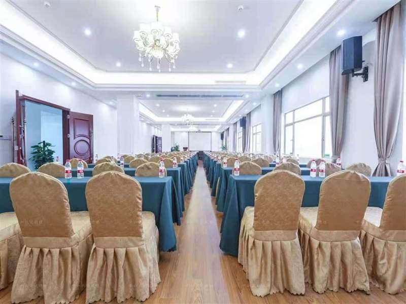 um salão de banquetes com mesas e cadeiras azuis e um lustre em Vienna Hotel Heyuan Hongxing Road em Heyuan