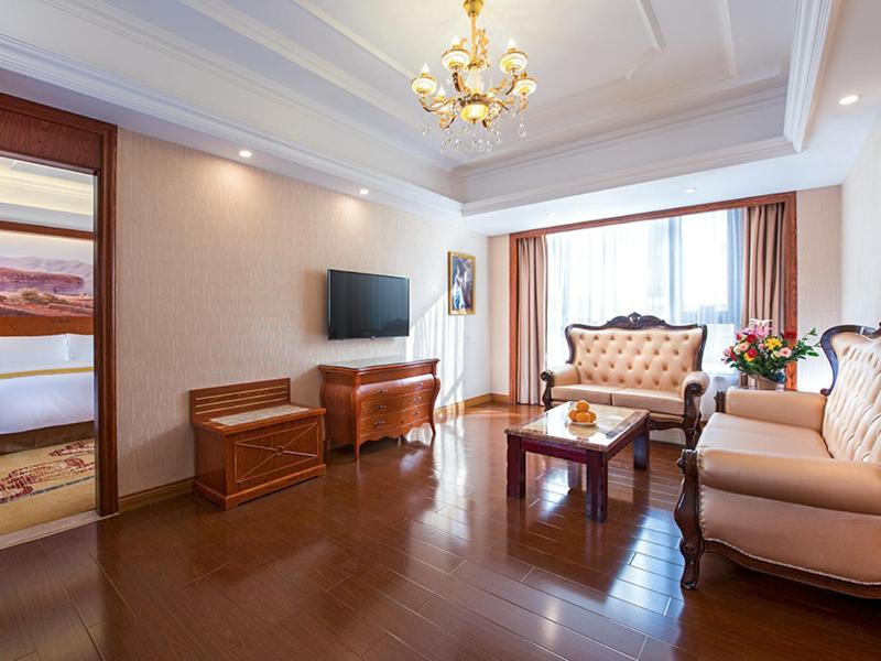 Vienna International Hotel Jieyang Yangmei Yudu في Jieyang: غرفة معيشة مع أريكة وتلفزيون