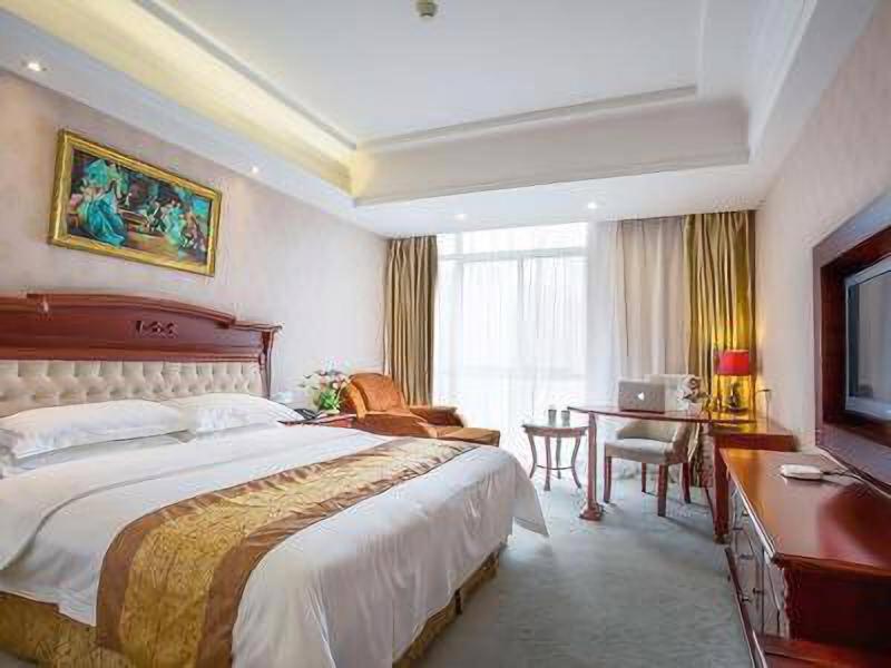 a hotel room with a large bed and a desk at Vienna Hotel Suzhou fairyland in Suzhou