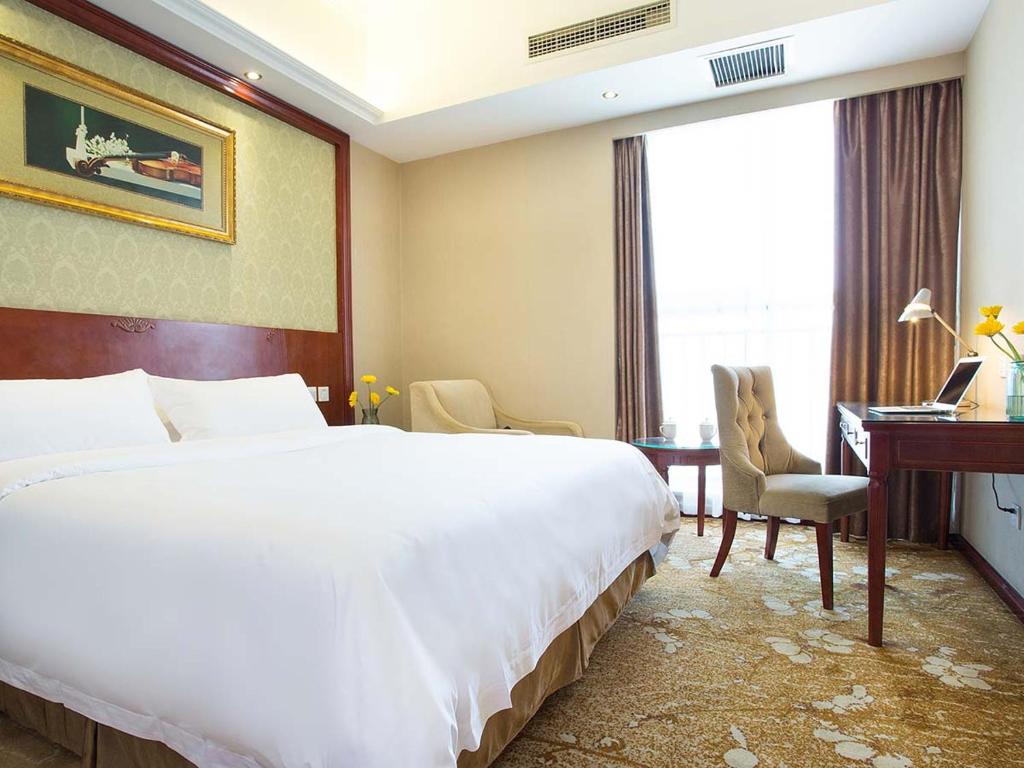 ein Hotelzimmer mit einem großen Bett und einem Schreibtisch in der Unterkunft Vienna Hotel Chengdu Exhibition Centre in Chengdu