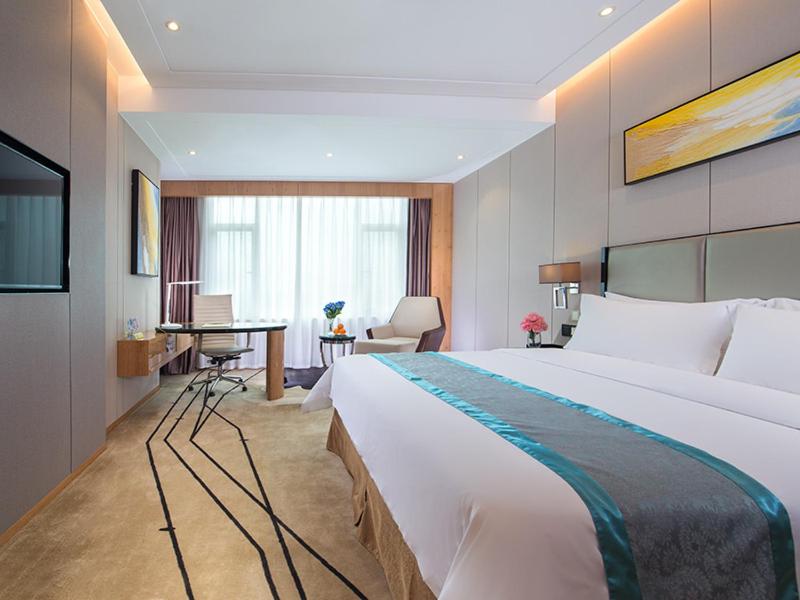 a hotel room with a large bed and a desk at Vienna International Hotel Foshan The World of Flowers in Shunde