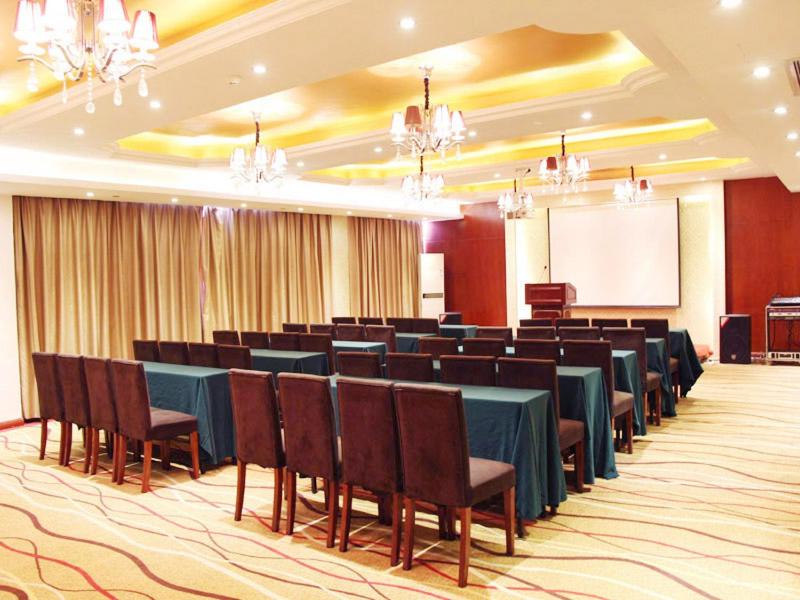 a conference room with tables and chairs and a screen at Vienna International Hotel Ningbo Wanda in Ningbo