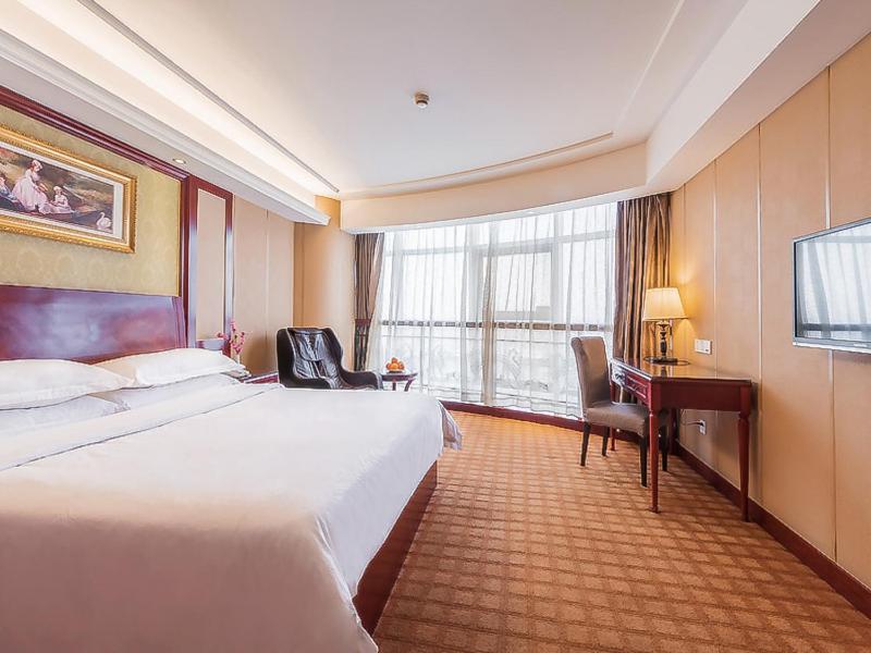 Habitación de hotel con cama grande y escritorio. en Vienna Hotel Shanghai Baoshan Wusong, en Shanghái