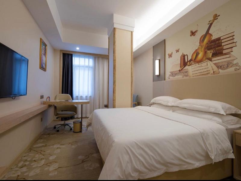 a hotel room with a bed and a desk and a television at Vienna Hotel Shenzhen Pingji Ave in Longgang