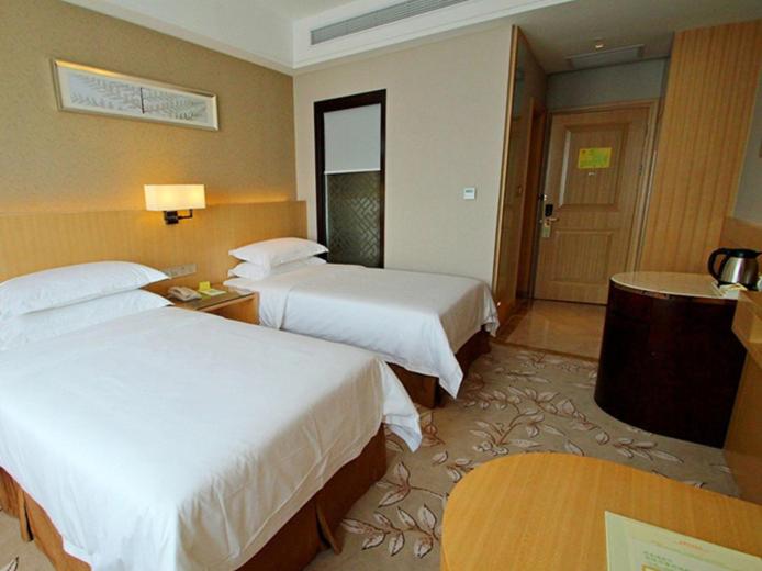 a hotel room with two beds and a table at Vienna Hotel Waigaoqiao in Shanghai