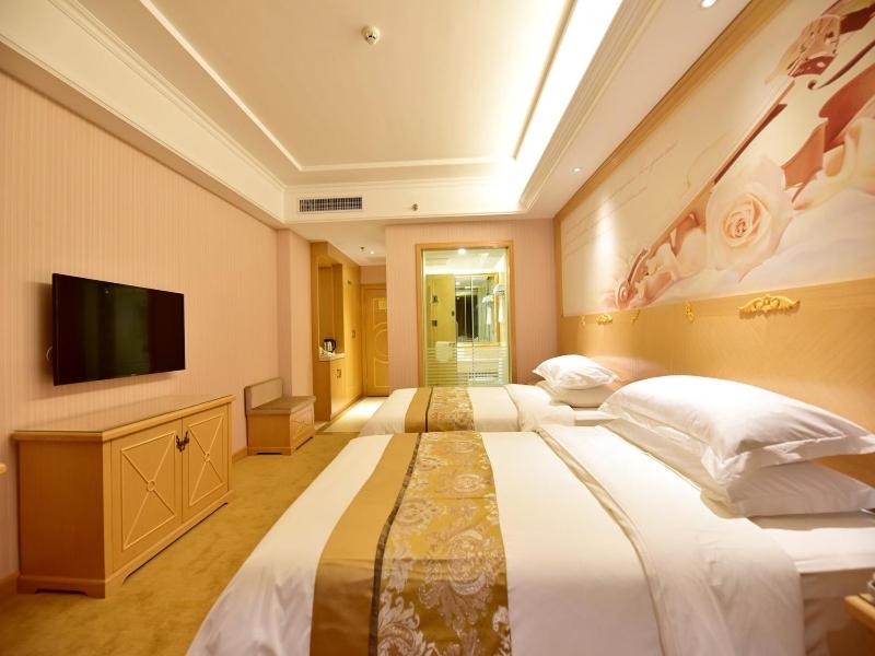 a large bedroom with two beds and a flat screen tv at Vienna Hotel Xining Shengli Road in Xining