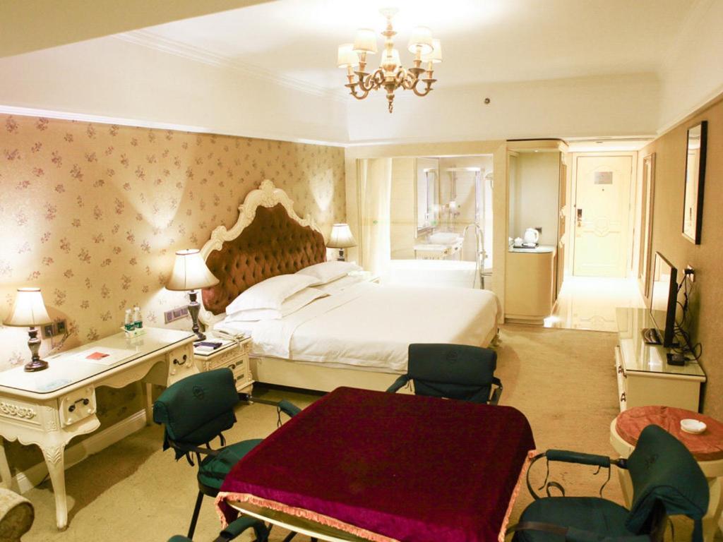 sypialnia z łóżkiem, stołem i krzesłami w obiekcie Vienna Hotel Yongzhou Zhiyuan New Bund w Yongzhou