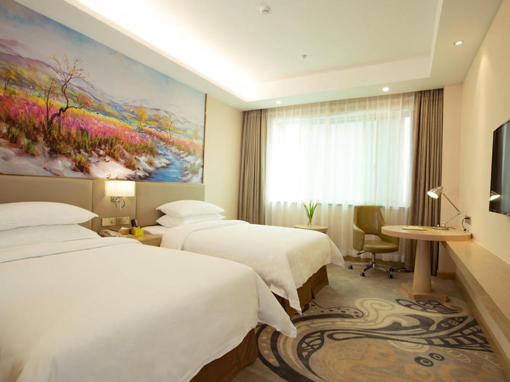 Vienna International Hotel Xian High Technology Road في شيان: غرفه فندقيه سريرين ولوحه