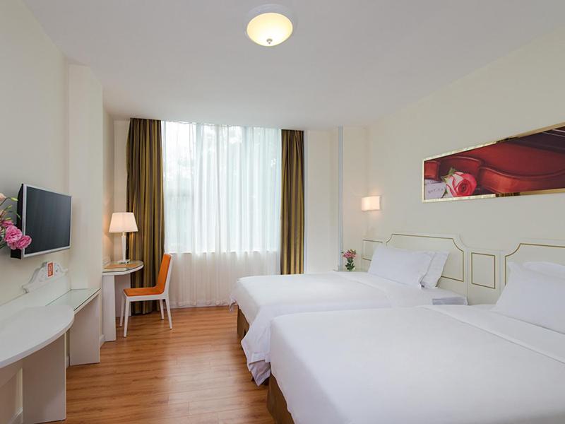 a white hotel room with two beds and a desk at Vienna 3 Best Hotel Shenzhen Shazui Road in Shenzhen