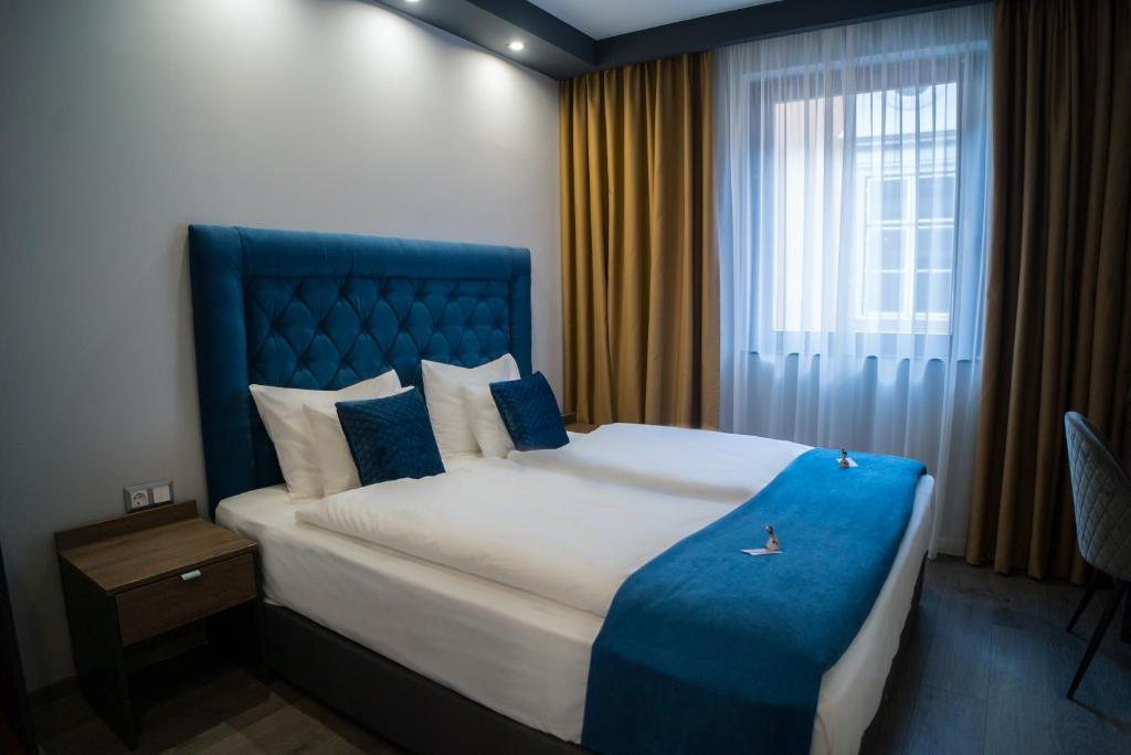 1 dormitorio con 1 cama con cabecero azul y ventana en Hotel Palatinus, en Sopron