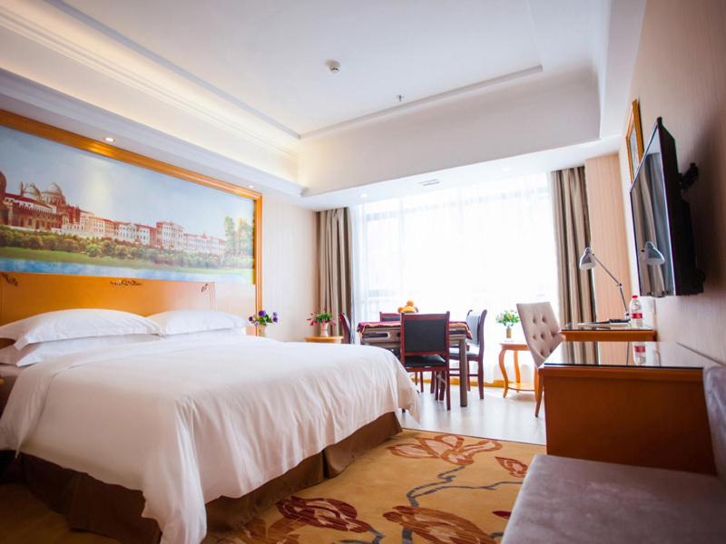 a hotel room with a large bed and a desk at Vienna Hotel Jiangxi Yichun City Hall in Yichun