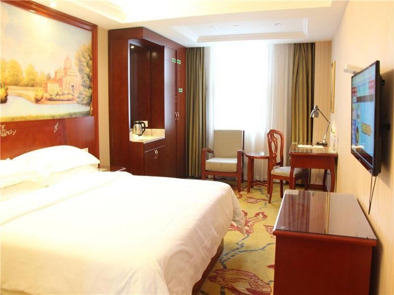 Vienna International Hotel Ningbo South Huancheng Road في نينغبو: غرفة في الفندق مع سرير ومكتب