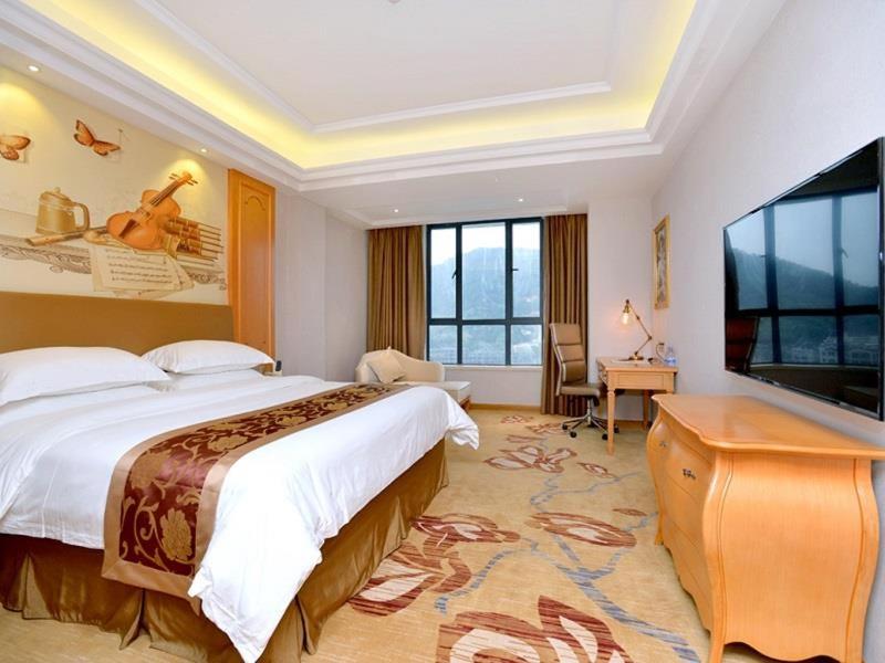 a bedroom with a large bed and a flat screen tv at Vienna Hotel Shantou Chaoyang Mianxi Road in Shantou