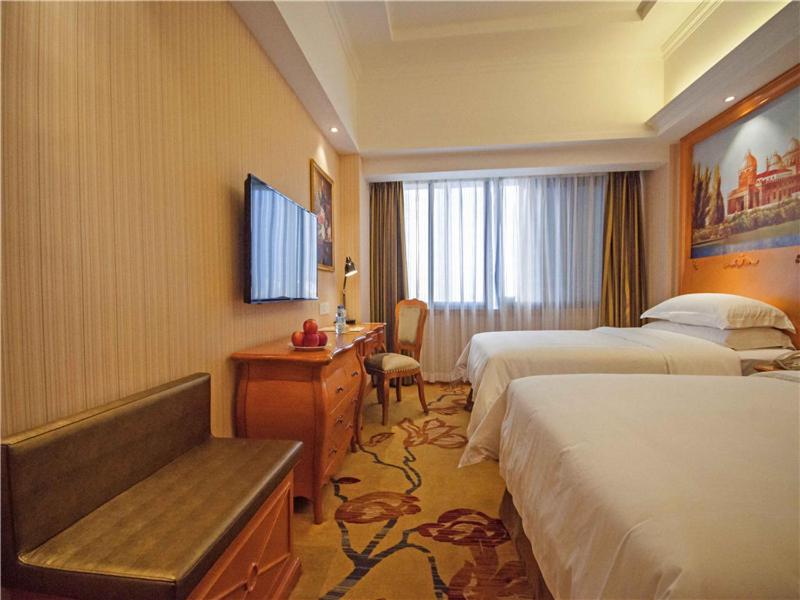 a hotel room with two beds and a desk at Vienna Hotel Yulin Jincheng Zhenlin in Yulin