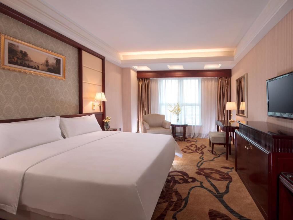 a hotel room with a large bed and a television at Vienna Hotel Foshan Nanzhuang Avenue in Foshan