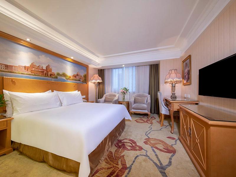 a hotel room with a large bed and a television at Vienna International Hotel Beijing GuangAnMen in Beijing